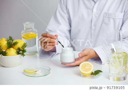 Lemon extract with sliced lemon transparent podium in laboratory , petri dish in a white background , green leaf in a test tube and doctor for cosmetic jar advertising , photography science concept Lemon extract with sliced lemon transparent podium in laboratory , petri dish in a white background , green leaf in a test tube and doctor for cosmetic jar advertising , photography science concept 91739105