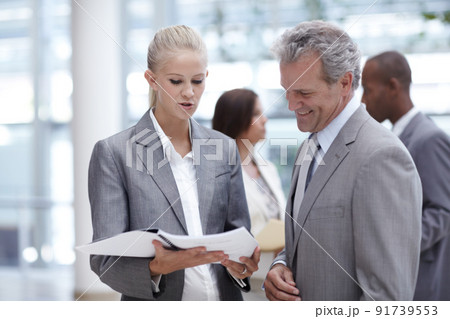 Seeking his respected advice. A pretty businesswoman presenting a binder to an impressed senior executive. Seeking his respected advice. A pretty businesswoman presenting a binder to an impressed senior executive. 91739553