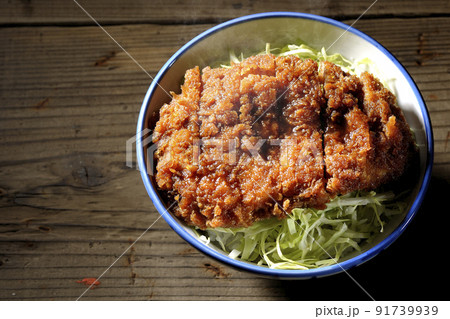 繊切りキャベツの上にたっぷりのソースが絡んだカツが乗っている熱々ソースかつ丼を俯瞰で撮影 91739939