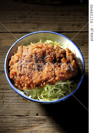 繊切りキャベツの上にたっぷりのソースが絡んだカツが乗っている熱々ソースかつ丼を俯瞰で撮影 91739940