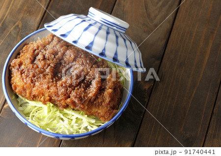 繊切りキャベツの上にたっぷりのソースが絡んだカツが乗っている熱々ソースかつ丼を俯瞰で撮影 91740441