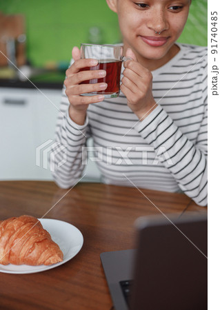 Close up shot of pretty young mixed race woman holding cup of tea sitting at table indoor Close up shot of pretty young mixed race woman holding cup of tea sitting at table indoor 91740485
