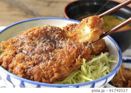 繊切りキャベツの上にたっぷりのソースが絡んだカツが乗っている熱々ソースかつ丼と味噌汁と漬物 91740527