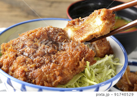 繊切りキャベツの上にたっぷりのソースが絡んだカツが乗っている熱々ソースかつ丼と味噌汁と漬物 91740529