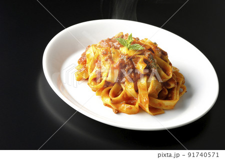 平打ちパスタのフィットチーネとトマトソースがよく絡んだ熱々ボロネーゼを黒背景で撮影 91740571