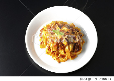 平打ちパスタのフィットチーネとトマトソースがよく絡んだ熱々ボロネーゼを黒背景で俯瞰撮影 91740613