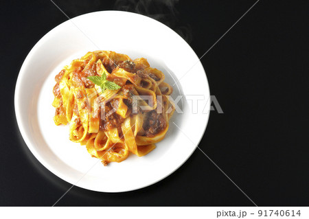 平打ちパスタのフィットチーネとトマトソースがよく絡んだ熱々ボロネーゼを黒背景で俯瞰撮影 91740614