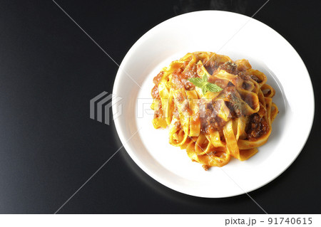 平打ちパスタのフィットチーネとトマトソースがよく絡んだ熱々ボロネーゼを黒背景で俯瞰撮影 91740615