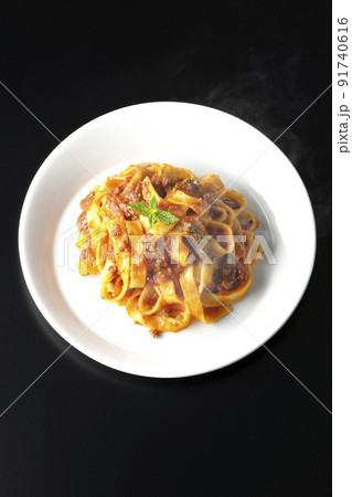 平打ちパスタのフィットチーネとトマトソースがよく絡んだ熱々ボロネーゼを黒背景で俯瞰撮影 91740616
