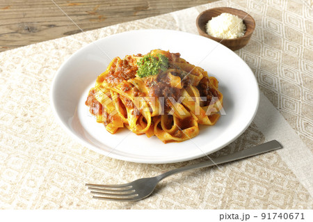 平打ちパスタのフィットチーネとトマトソースがよく絡んだ熱々ボロネーゼにパルメザンチーズを添えて 91740671