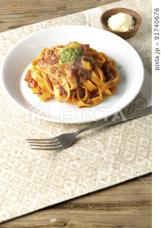 平打ちパスタのフィットチーネとトマトソースがよく絡んだ熱々ボロネーゼにパルメザンチーズを添えて 91740676