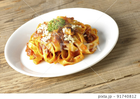 平打ちパスタのフィットチーネとトマトソースがよく絡んだ熱々ボロネーゼにパルメザンチーズがけ 91740812