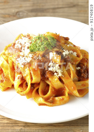 平打ちパスタのフィットチーネとトマトソースがよく絡んだ熱々ボロネーゼにパルメザンチーズがけ 91740819