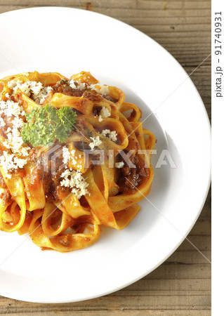 平打ちパスタのフィットチーネとトマトソースがよく絡んだボロネーゼにパルメザンチーズがけを俯瞰で撮影 91740931