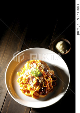 平打ちパスタのフィットチーネとトマトソースがよく絡んだボロネーゼにパルメザンチーズがけを俯瞰で撮影 平打ちパスタのフィットチーネとトマトソースがよく絡んだボロネーゼにパルメザンチーズがけを俯瞰で撮影 91741063