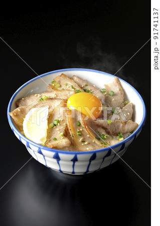 カットレモンと卵黄が乗った熱々豚トロ丼、焼き肉丼を黒背景で撮影 カットレモンと卵黄が乗った熱々豚トロ丼、焼き肉丼を黒背景で撮影 91741137