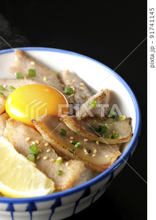 カットレモンと卵黄が乗った熱々豚トロ丼、焼き肉丼を黒背景で撮影 カットレモンと卵黄が乗った熱々豚トロ丼、焼き肉丼を黒背景で撮影 91741145