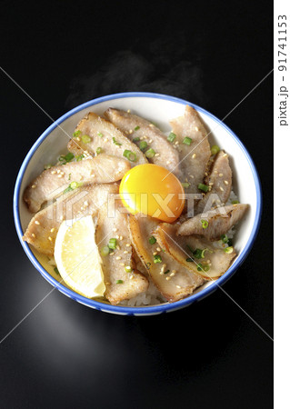 カットレモンと卵黄が乗った熱々豚トロ丼、焼き肉丼を黒背景で俯瞰撮影 91741153