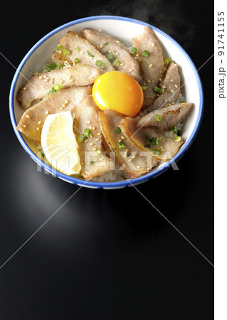 カットレモンと卵黄が乗った熱々豚トロ丼、焼き肉丼を黒背景で俯瞰撮影 91741155