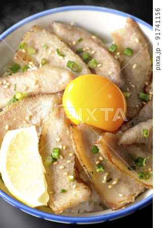 カットレモンと卵黄が乗った熱々豚トロ丼、焼き肉丼を黒背景で俯瞰撮影 91741156