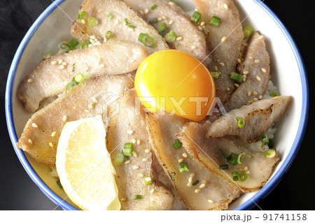 カットレモンと卵黄が乗った熱々豚トロ丼、焼き肉丼を黒背景で俯瞰撮影 91741158