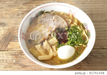 大きなチャーシューとメンマやゆで卵や万能ねぎと辛味噌が乗っている熱々豚骨醤油ラーメンを俯瞰で撮影 91741348