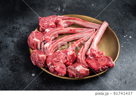 Lamb chop rib steak, raw mutton meat cutlet in golden plate. Black background. Top view 91741437