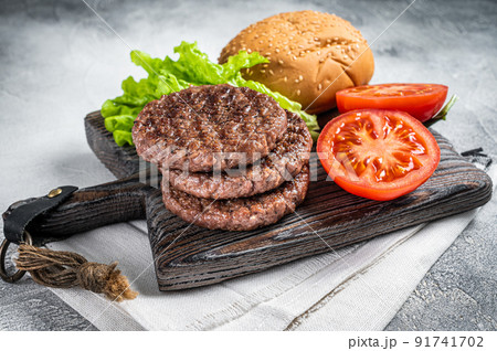 Fried cutlet for burger with vegetables and spices on wooden board. White background. Top view Fried cutlet for burger with vegetables and spices on wooden board. White background. Top view 91741702