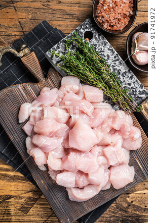 Raw chicken fillet cut into cubes, Uncooked sliced poultry meat, on wooden board. Wooden background. Top view 91741972