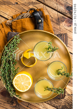 Limoncello shots, Italian lemon liqueur. Wooden background. Top view Limoncello shots, Italian lemon liqueur. Wooden background. Top view 91742046