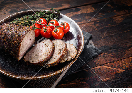 Sliced roast pork roulade - Porchetta on a plate with spices. Wooden background. Top view. Copy space Sliced roast pork roulade - Porchetta on a plate with spices. Wooden background. Top view. Copy space 91742146