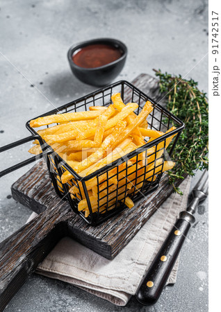 Basket of Fried French fries potatoes with salt on wooden board. Gray background. Top view Basket of Fried French fries potatoes with salt on wooden board. Gray background. Top view 91742517