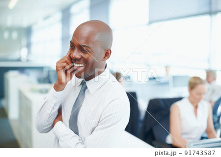 Catching up with his clientele. Positive young African executive on his mobile at work. 91743587