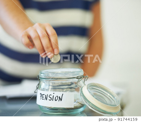Saving penny for penny. A person putting a penny in a jar that is labeled amp039Pensionamp039. 91744159