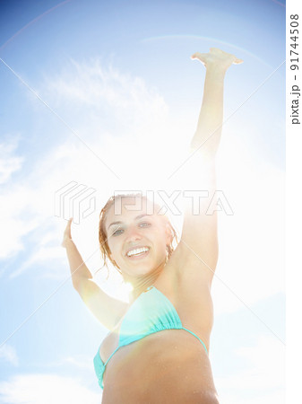 Young woman in bikini excited about her summer vacation. Happy young bikini woman with hands raised against the sunny sky. Young woman in bikini excited about her summer vacation. Happy young bikini woman with hands raised against the sunny sky. 91744508
