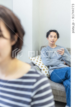 ソファでスマホを使う男性 91744773