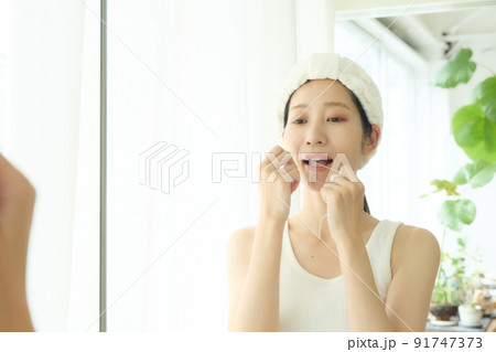 洗面所でデンタルフロスをする女性 洗面所でデンタルフロスをする女性 91747373
