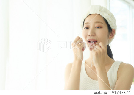 洗面所でデンタルフロスをする女性 91747374