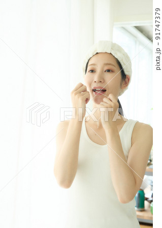 洗面所でデンタルフロスをする女性 洗面所でデンタルフロスをする女性 91747379