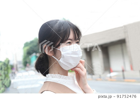 マスクをつけてマスクを触っている女性横顔 91752476