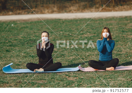 Beautiful girls training. Girls in a summer park. Lady make a yoga. Coronavirus theme 91752577