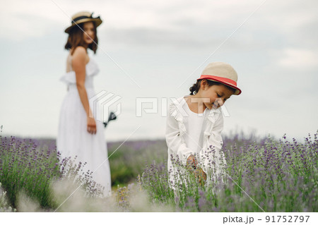 Mother with little daughter on lavender background. Beautiful woman and cute baby playing in meadow field. Family holiday in summer day. 91752797