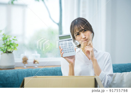 荷物の前で計算機を持つ若い主婦 91755798