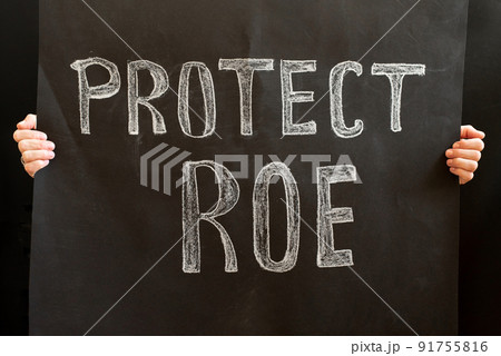 A woman's hands hold a Protect ROE placard. a woman stands up for her rights with a placard. The concept of protests in the United States. Women's rights and feminists fight for their rights 91755816