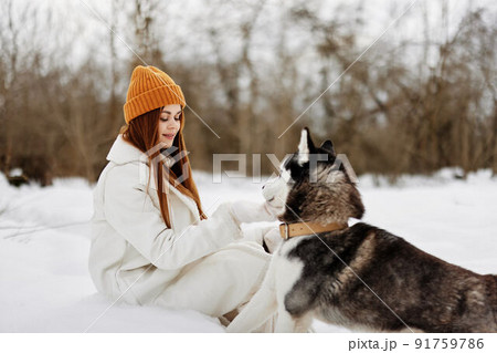 Happy young woman outdoors in a field in winter walking with a dog winter holidays 91759786