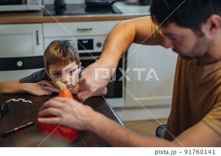 Caucasian man with his cute 6 year old son drawing out eyes on a pumpkin to make traditional Jack lantern. Caucasian man with his cute 6 year old son drawing out eyes on a pumpkin to make traditional Jack lantern. 91760141