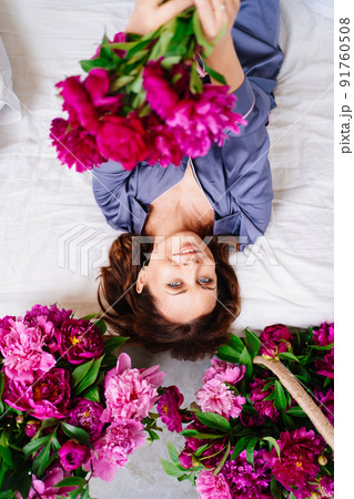 happy morning. a woman in pajamas in bed with a peonies. 91760508