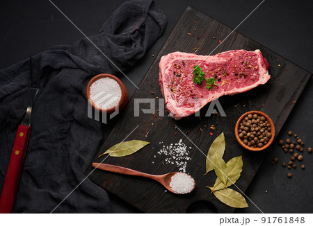 Fresh raw piece of beef meat, striploin steak on a black background, top view. Marbled piece of meat 91761848