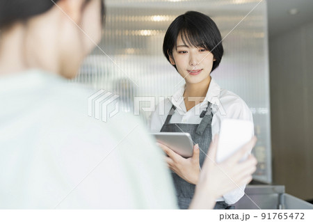 カフェ スタッフにスマートフォンを見せる女性 カフェ スタッフにスマートフォンを見せる女性 91765472