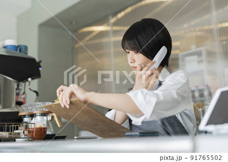 カフェ 電話をする女性スタッフ 91765502